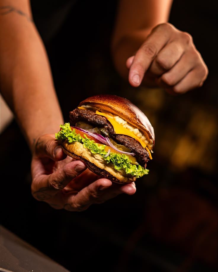 Buzz Salad: burger duplo com cheddar, alface, tomate e cebola roxa na mão do chapeiro